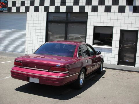 1992 Ford Crown Victoria - This maroon sedan is parked in front of a building with a distinctive black and white checkered facade.