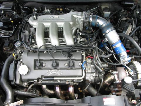 1996 Ford Probe - Close-up view of a modified Ford V6 engine, a turbocharger and custom intake piping.