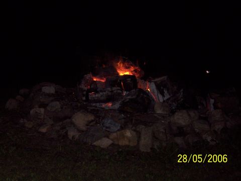 1996 Ford Probe - A bonfire burns brightly at night, with rocks and grass visible in the foreground.