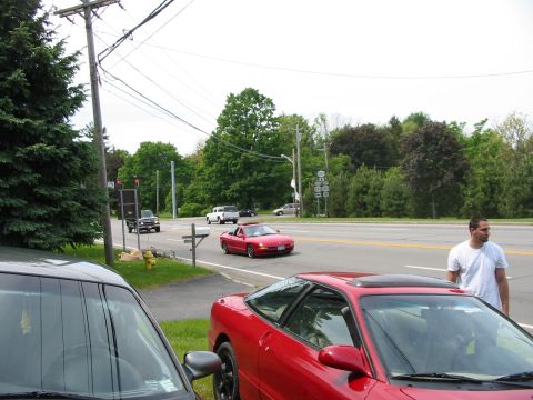 1996 Ford Probe - A red 1996 Ford Probe convertible is seen driving on a street with other vehicles present.