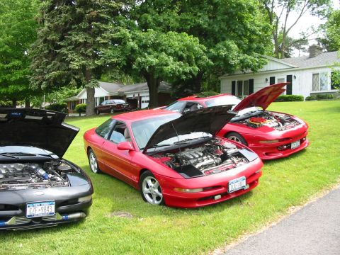 1996 Ford Probe - Three Ford Probes are parked on a lawn with their hoods open, revealing their engines.
