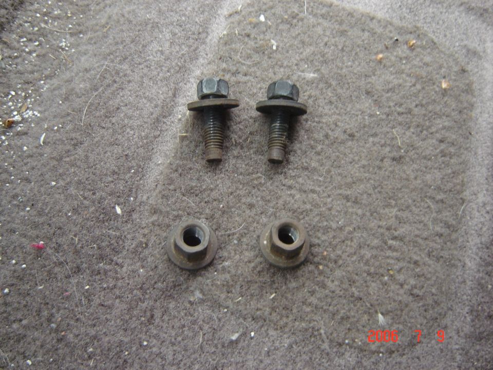 Two flanged hex bolts and two flanged nuts on gray carpet
