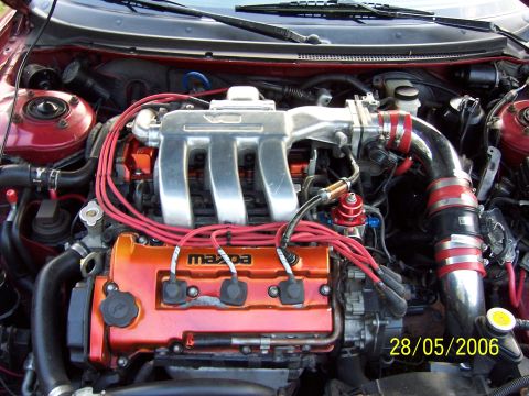 1996 Ford Probe - Close-up of a car's engine bay, a Mazda branded valve cover and various engine components.