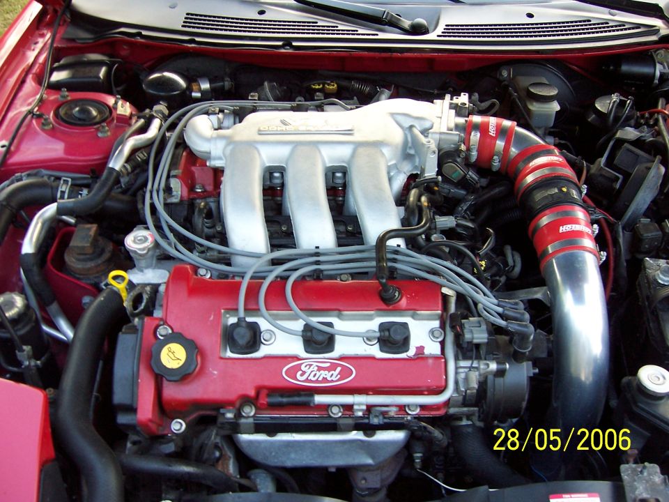 Red engine bay with a Ford engine, silver intake piping, and a date stamp of 28/05/2006