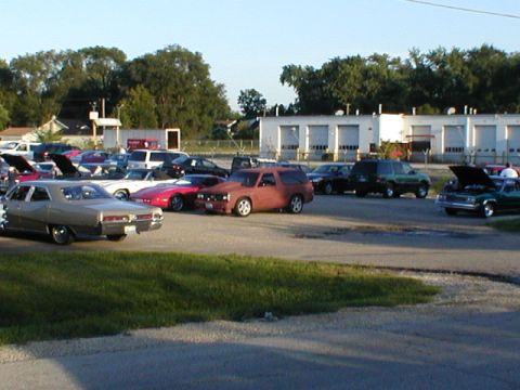 1998 Ford Taurus - A variety of vehicles are parked in a lot outside a building with multiple garage doors.