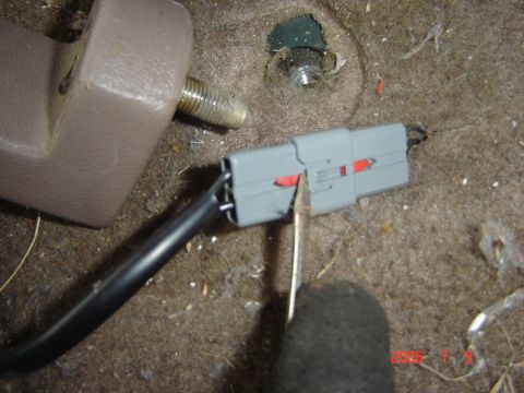 1993 Ford Bronco - Close-up of a seat bolt and an electrical connector on a vehicle's carpeted floor.