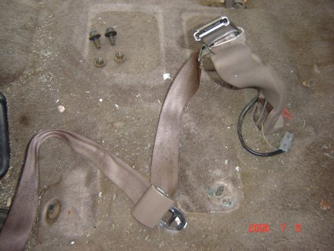 1993 Ford Bronco - Vehicle interior showing a seatbelt assembly and loose bolts on the floor.