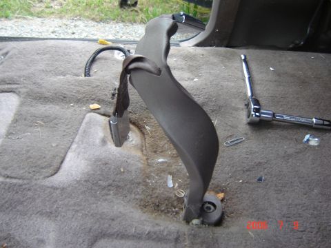 1993 Ford Bronco - Close-up of a seatbelt anchor point inside a vehicle, with a ratchet tool on the floor.