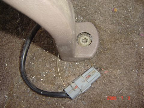 1993 Ford Bronco - Close-up of a vehicle's interior showing a seat mounting bracket and its associated wiring harness connector.