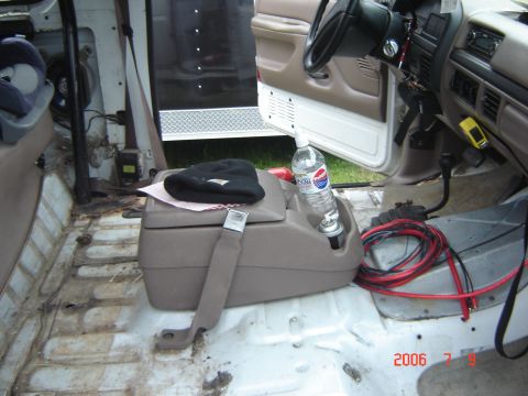 1993 Ford Bronco - Interior view of a vehicle's cabin, showing a center console jump seat, a bottle of Pepsi, and loose wiring on the floor.