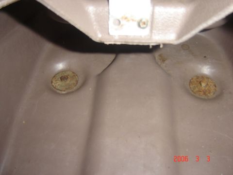 1993 Ford Bronco - Close-up of the floor pan with two rusted mounting bolts visible.