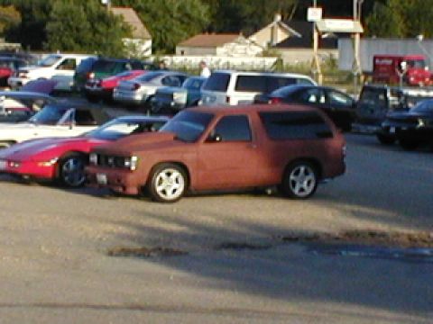 1998 Ford Taurus - A rusty red SUV with aftermarket wheels is parked in a lot with other vehicles.