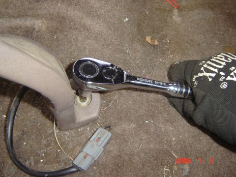 1993 Ford Bronco - Socket wrench is used to remove a seat bolt, with a gray electrical connector nearby.