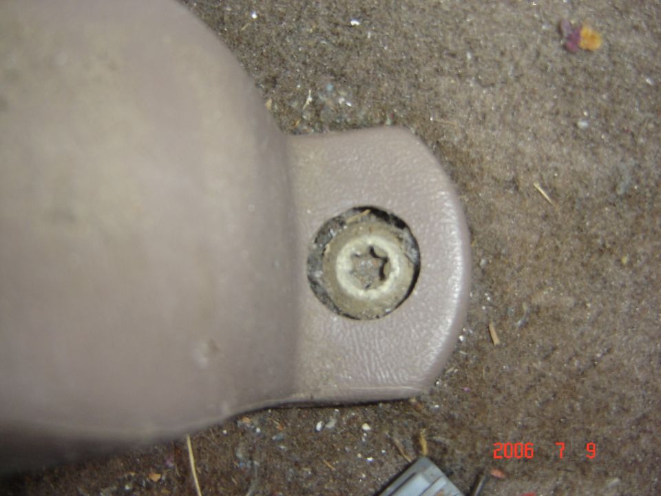 Tan seatbelt anchor cover with recessed Torx bolt, dated 2006