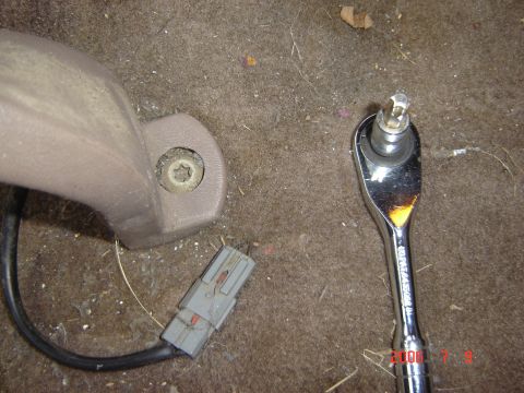 1993 Ford Bronco - Close-up of a car seat mounting bolt and a ratchet tool on the carpeted floor.