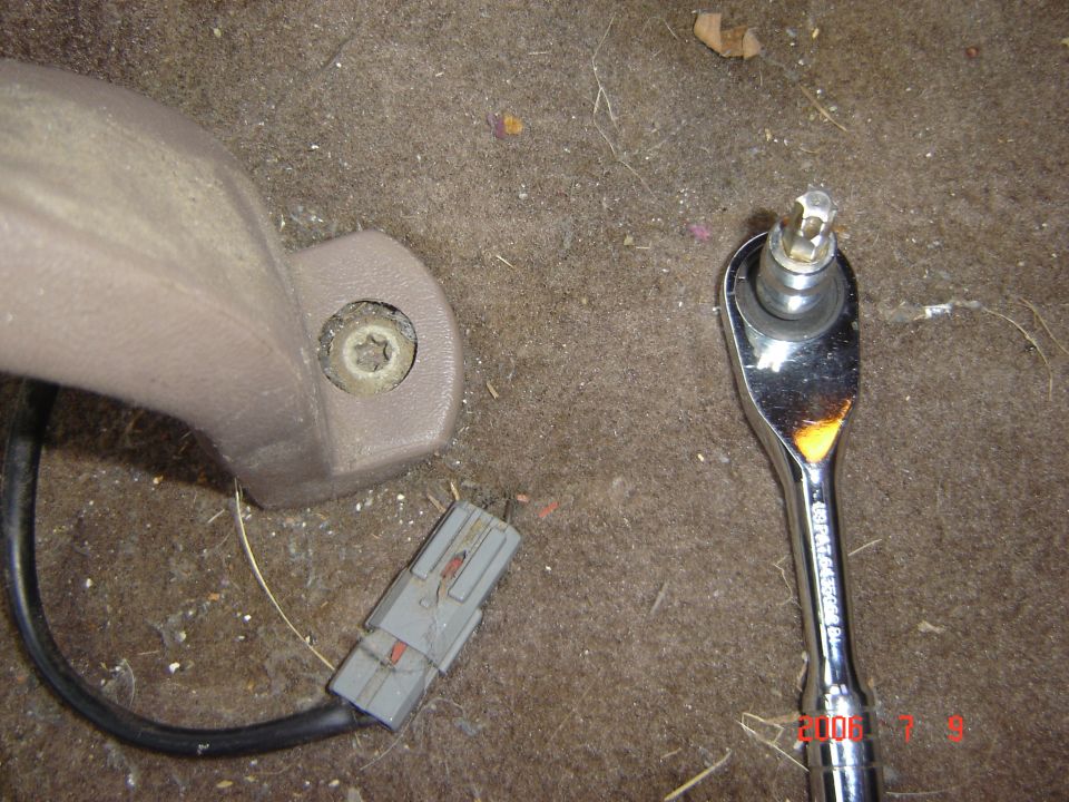 Tan trim piece with Torx screw and wiring next to a chrome ratchet on carpet