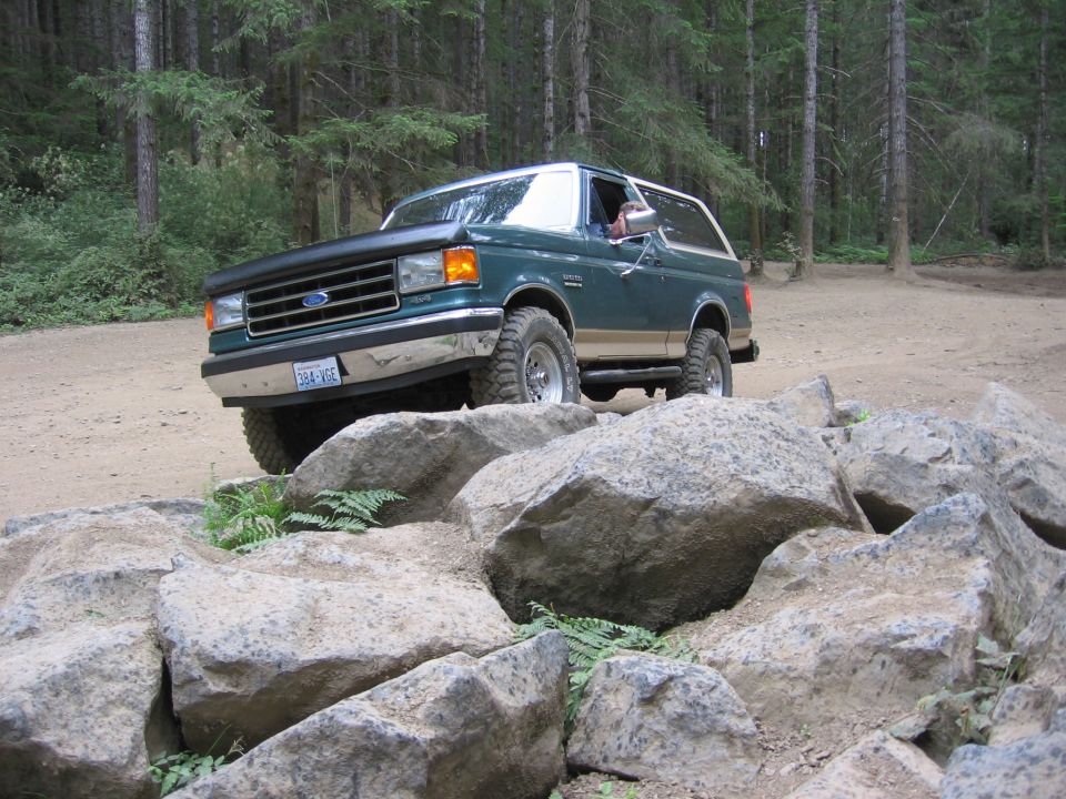 Green 1990 Ford Bronco navigating rocky terrain