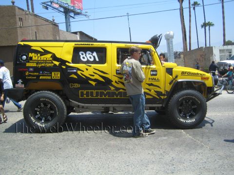 1990 Ford Bronco - Side view of a yellow lifted Hummer H2 number 861 with black tribal graphics, sponsor decals and BFGoodrich tires on a street.