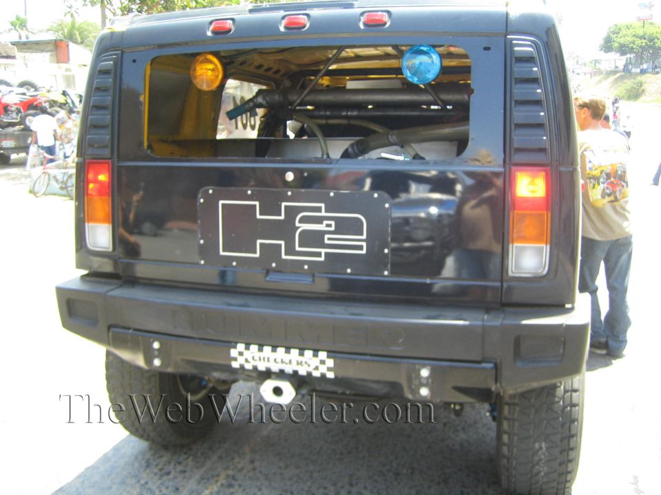 Rear view of a black Hummer H2 with H2 tailgate plate and amber/red tail lights