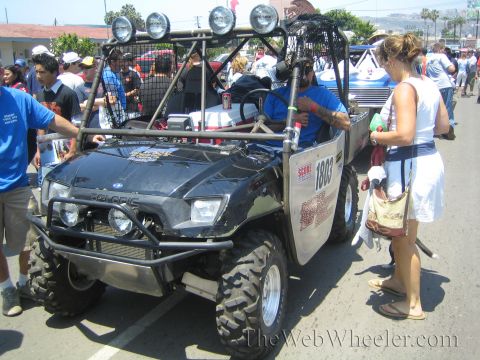 1990 Ford Bronco - Front three-quarter view of a black Polaris side-by-side UTV number 1803 with a roof light bar among spectators on a street.