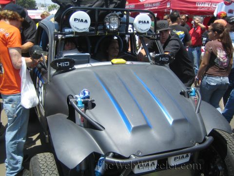 1990 Ford Bronco - Front view of a gray two-seat off-road race buggy with PIAA roof lights and a blue nitrous bottle, surrounded by people in a pit.