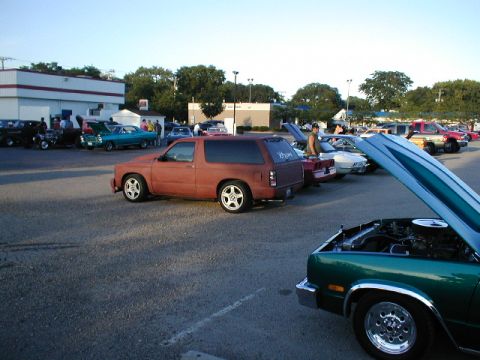 1998 Ford Taurus - Several vehicles are gathered in a parking lot, with one red SUV prominently featured in the foreground.