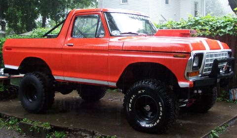1978 Ford Bronco - This orange 1978 Ford Bronco features a hood scoop and off-road tires, seen in the rain.