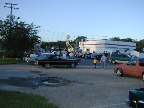 1998 Ford Taurus - A black convertible is seen from the side at a car meet, with several other vehicles and people in the background.