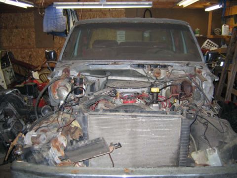 1986 Ford C-350 (Centurion Conversions) - The engine bay of a Ford truck is shown with many parts removed, revealing the engine and radiator.