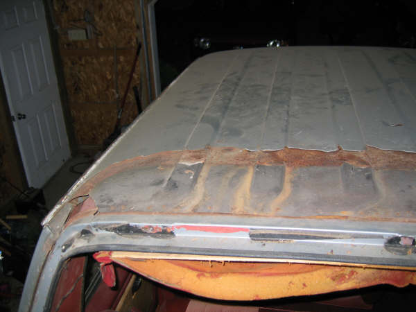 Rusted rear roof seam of a truck cab with cap removed, exposed pitted metal and old sealant