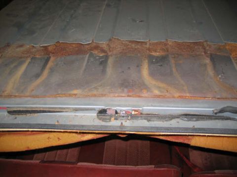 1986 Ford C-350 (Centurion Conversions) - The interior of a vehicle shows worn seats and a heavily rusted roof panel.