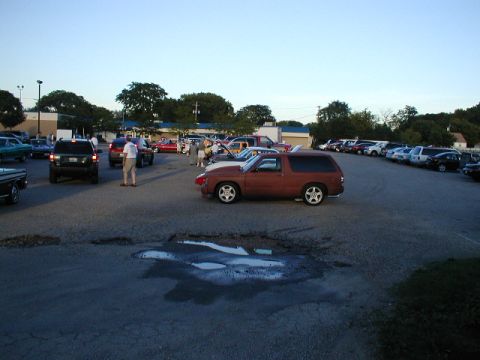 1998 Ford Taurus - A gathering of vehicles in a parking lot under a clear sky.