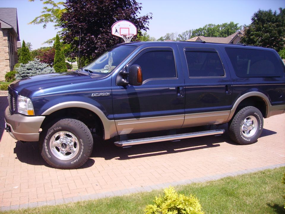 Blue Ford Excursion 4x4 SUV with tan two-tone parked on a brick driveway
