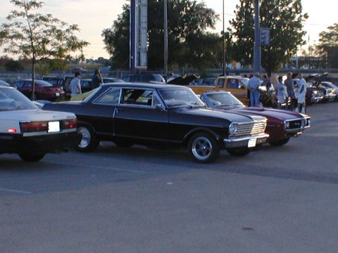 1998 Ford Taurus - A black coupe with classic styling is parked among other vehicles at an outdoor gathering.
