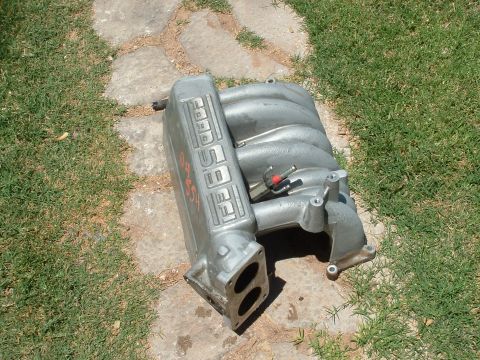 1990 Ford Bronco - Ford EFI intake manifold shown on grass and stone patio.