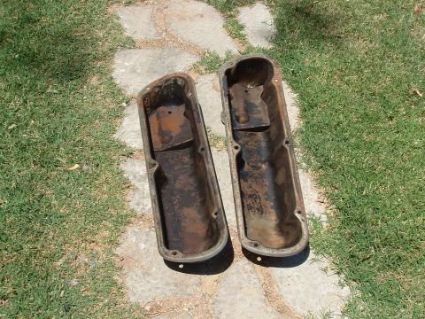 1990 Ford Bronco - Two used valve covers are shown resting on a path made of stones and grass.