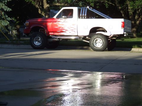 1988 Ford F-150 - This lifted pickup truck has a two-tone paint job with red and white sections and flame graphics.