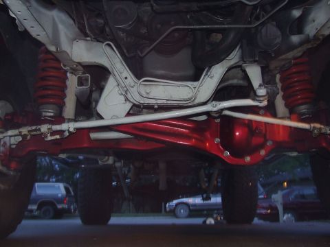 1988 Ford F-150 - Undercarriage view shows a red-painted differential and suspension components, with other vehicles visible in the background.
