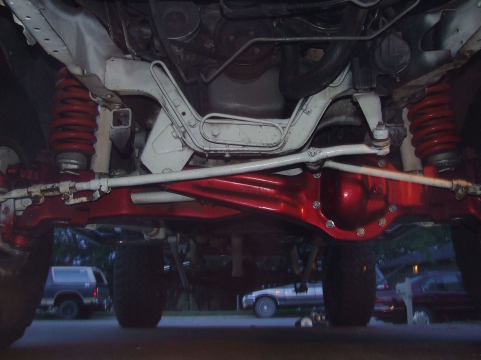 Undercarriage view of red-painted differential and suspension components on a truck
