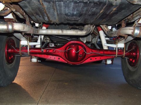 1988 Ford F-150 - Close-up of a custom red painted rear axle assembly on a vehicle's underside.