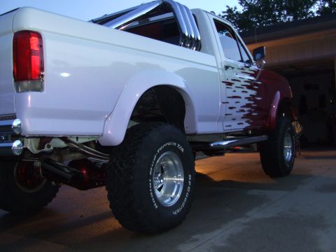1988 Ford F-150 - This lifted pickup truck has custom flame graphics and large off-road tires.