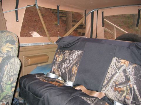 1990 Ford Bronco - The interior of a vehicle is shown with camouflage seat covers and a view of the outdoors through the windows.