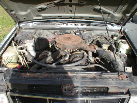 1998 Ford Taurus - The engine bay of a vehicle, a V8 engine and air cleaner. The grille shows signs of rust.