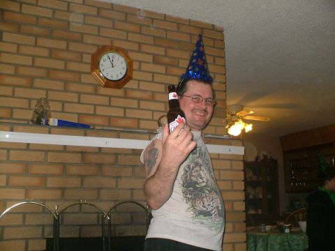 1989 Ford Bronco - Man in party hat holds a beer bottle in front of a brick fireplace.