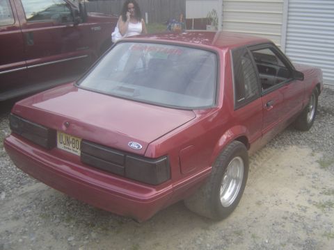 1988 Ford Bronco - A maroon Ford Mustang coupe is parked next to a maroon truck.