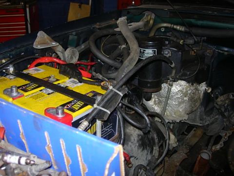 1993 Ford Bronco - Engine bay details with dual batteries and various hoses and wiring. The vehicle's green exterior is partially visible.