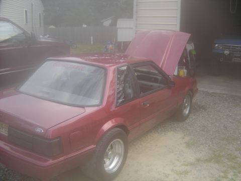 1988 Ford Bronco - Red coupe with hood open, parked next to a maroon truck and a blue SUV in a driveway.