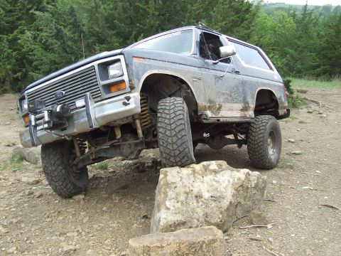 1986 Ford Bronco - A modified Ford Bronco is shown off-roading over large rocks.