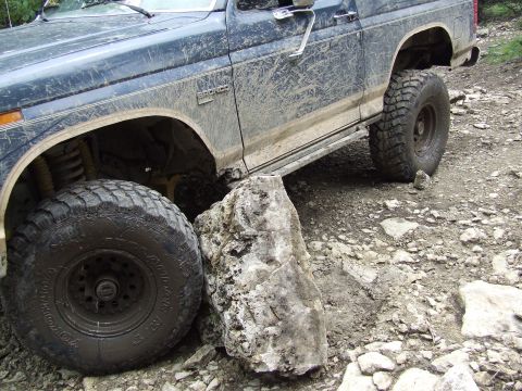 1986 Ford Bronco - Muddy 1986 Ford Bronco navigating rocky terrain.