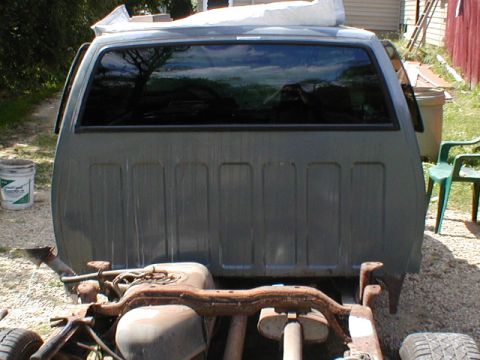 1998 Ford Taurus - The rear view of a gray pickup truck cab shows its ribbed bed paneling and large rear window.